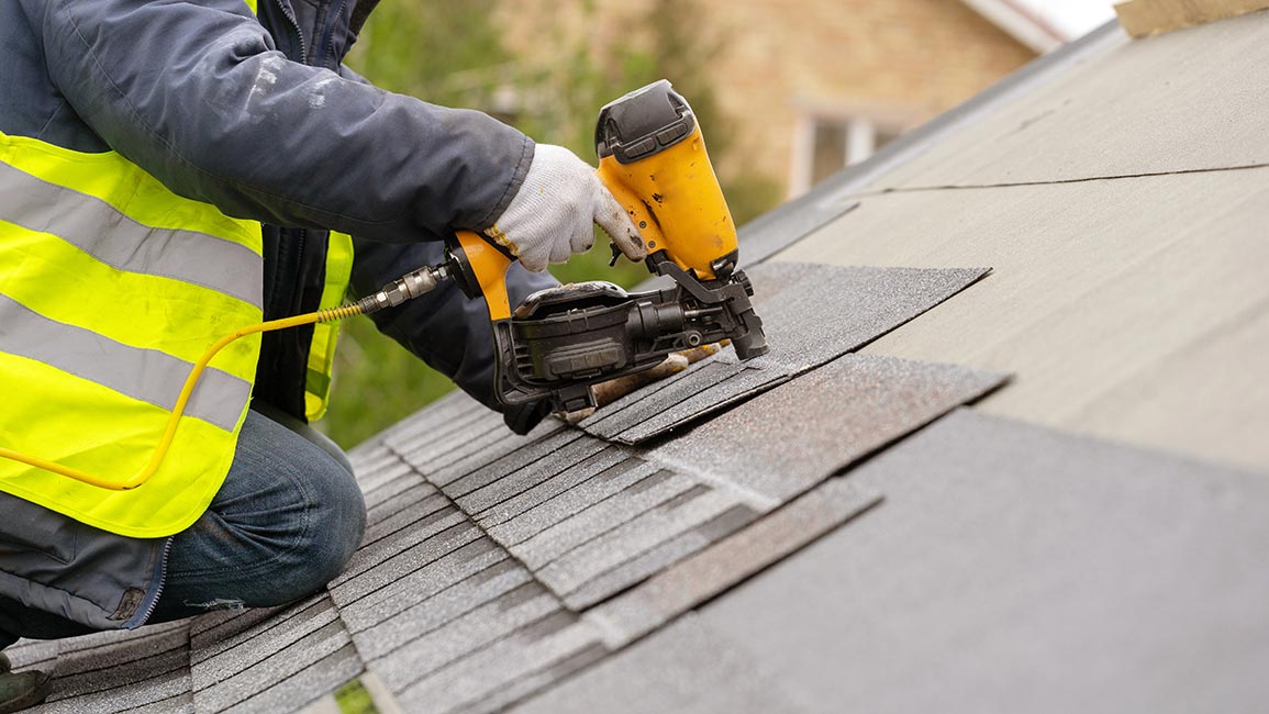 a roofer applying asphalt shingles to a roof