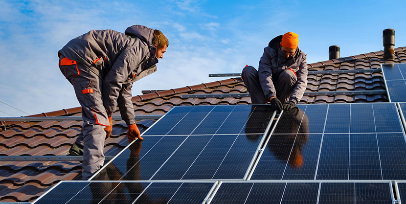 2 men working on installing solar panels onto a roof